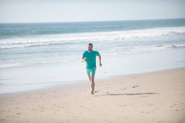 Man running on beach. Jogging on a sandy beach near sea or ocean.