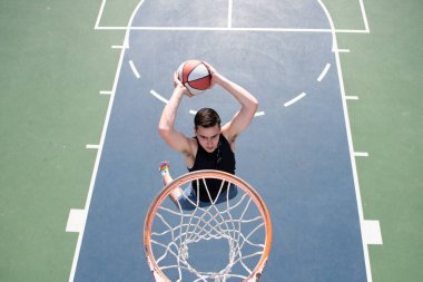 Basketbolcu. Spor ve basketbol. Adam zıplar ve topu sepete atar..