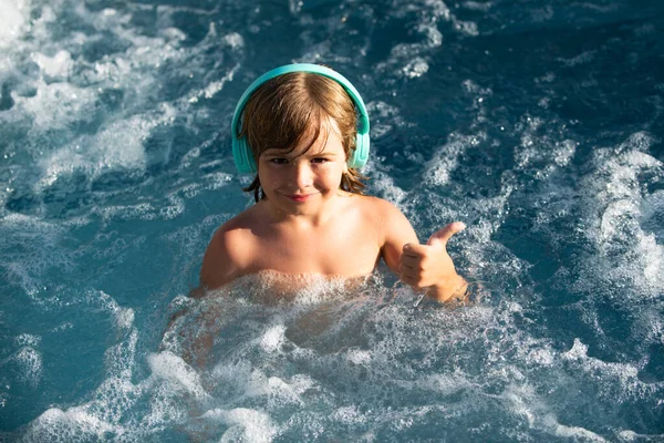 Niño feliz jugando en la piscina al aire libre en el caluroso día de verano. Los niños aprenden a nadar. Niño en el agua. Los niños juegan en el resort tropical. Vacaciones familiares en playa. — Foto de Stock