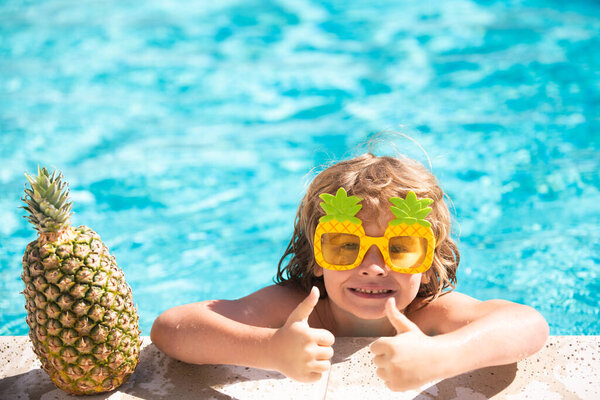 Child in swimming pool. Summer activity. Healthy kids lifestyle. Summer pineapple fruit.