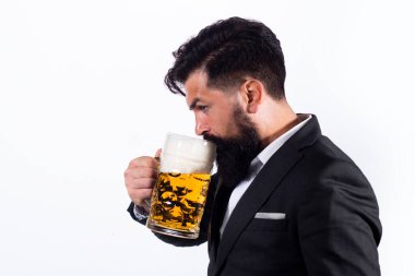 Klasik takım elbiseli adam bira içiyor. İş kıyafetli sakallı adam mutlu ve memnun görünüyor. Yüksek bardakta bira içen adamın portresi..