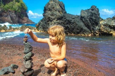 Çakıl taşı yapan tatlı çocuk deniz kıyısındaki volkanik bir kayanın üzerine yığılmış. Zen kavramı.