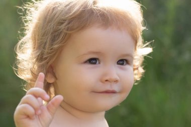 Güneşli bir günde yeşil doğa parkında şirin bir bebeğin portresi. Çocukluk ve ebeveynlik kavramı.