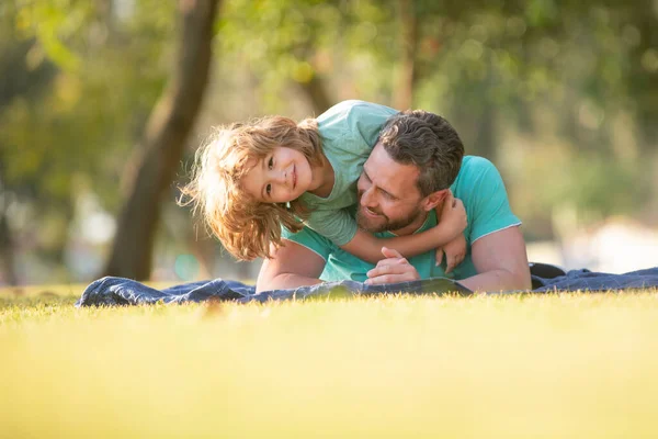 People having fun outdoors. Concept of happy vacation and friendly family. Happy father and son embracing and hugging enjoying summer time on vacation in a sunny park. — Stock Photo, Image