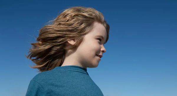 Roligt barnansikte på blå himmel med kopieringsutrymme, närbild. Ungar tittar bort, huvud porträtt. — Stockfoto