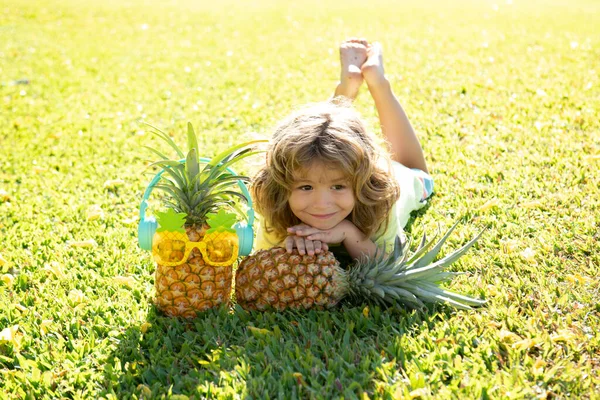 Child boy holding pineapple smiling with happy face in yard. Summer fruits. — Stock Photo, Image