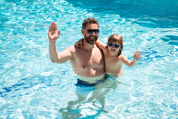 Vader en zoon zwemmen in het zwembad, zomerfamilie. Zwembadfeest. Kind met papa die in het zwembad speelt. Zomervakantie. Aquapark. Vader en zoon vrije tijd. — Stockfoto