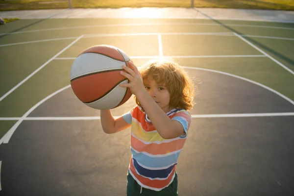 Criança menino jogando basquete com bola de cesta. — Fotografia de Stock