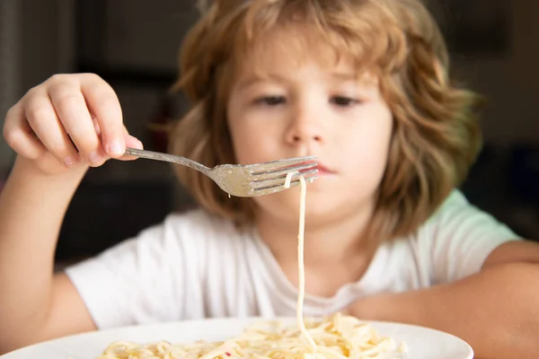 Portret van een schattig jongetje dat pasta eet, spaghetti. Sluit Kaukasische kinderen gezicht. Close-up hoofd van grappige jongen. — Stockfoto