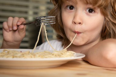Makarna, spagetti ve yakın plan yiyen sarışın bir çocuğun portresi. Tatlı çocuk suratı. Pozitif duygusal çocuk.