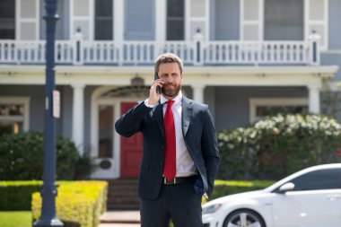 İş adamı cep telefonunu takım elbise giyip mesajlaşan bir uygulama kullanarak tutuyor. Genç şehirli profesyonel adam evde akıllı telefon kullanıyor. Emlakçı.