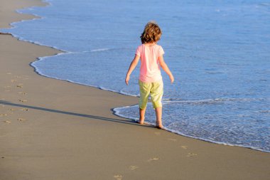 Çocuklar yaz tatilinde plajda. Yaz tatilinde sahildeki çocuk. Deniz, kum ve mavi gökyüzü. Mutlu çocuk deniz kenarında tatilde..