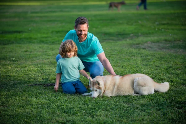 Pai e filho com cão no parque. Conceito de estilo de vida familiar feliz. — Fotografia de Stock