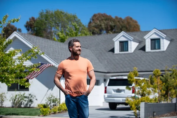 Porträt eines jungen, gut aussehenden Immobilienmaklers, der in der Nähe eines neuen Hauses steht. Makler und Haus. — Stockfoto