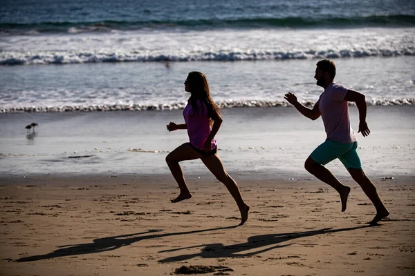 ビーチを走っているカップル。海のそばを走るスポーツマンとスポーツマン. — ストック写真