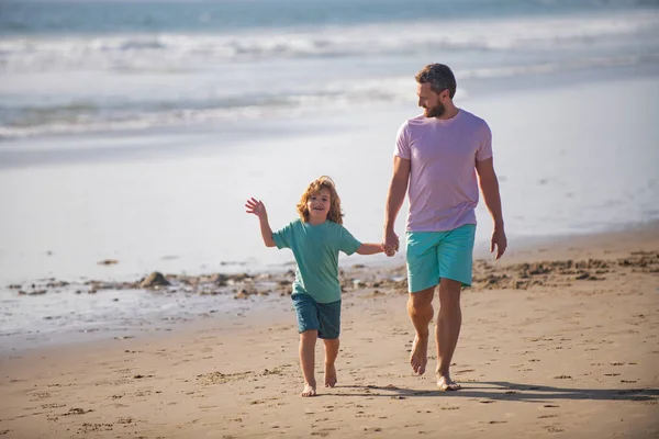 Pai e criança de mãos dadas e caminham juntos. Pai e filho caminhando na praia de verão. — Fotografia de Stock