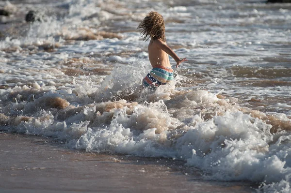 Niño saltando en olas marinas. Saltar por el agua salpicaduras de mar. Vacaciones de verano para niños. — Foto de Stock