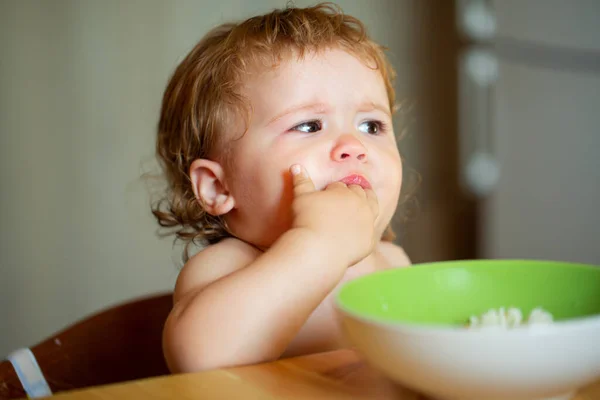 Portret van een schattig blank kind met lepel. Hongerige rommelige baby met bord na het eten puree. — Stockfoto