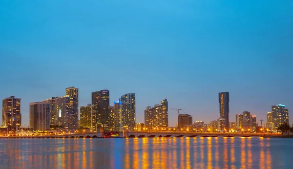 Ciudad de Miami Florida, panorama al atardecer con edificios comerciales y residenciales y puente en la bahía de Biscayne. Vista nocturna del horizonte. — Foto de Stock