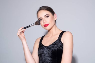 Güzel bir kadın makyaj fırçasıyla allık sürüyor. Güzellik portresini kapat..