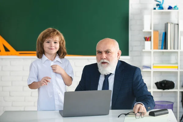 Profesora con colegial en clase. Alumno con portátil. Educación y aprendizaje. El maestro ayuda a aprender. Lecciones felices. Regreso a la escuela. —  Fotos de Stock