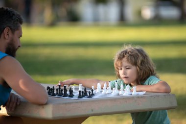 Baba ve oğul dışarıda satranç oynuyorlar. Çocuklar için oyunlar ve etkinlikler.