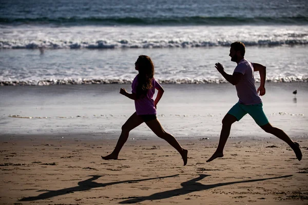 Молодий чоловік і жінка бігають по морю. Пара біжить на пляжі . — стокове фото