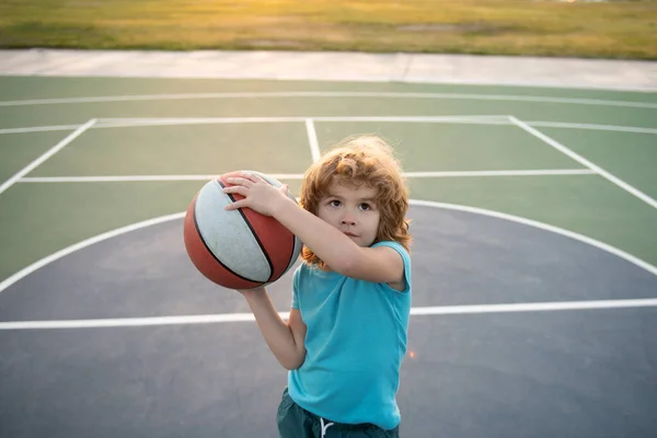 Barn som leker basket. Söt liten pojke som håller en korg boll försöker göra ett mål. Sport för barn. — Stockfoto