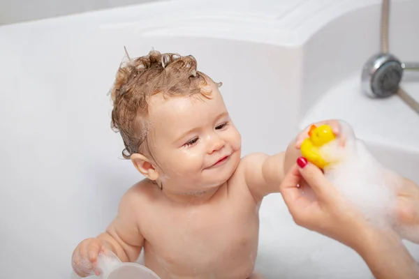 Child bubble bath. Funny baby kid bathed in foam and washing in bathtub at home.