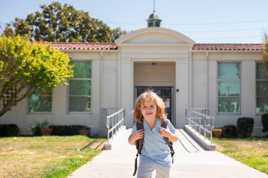 Mutlu gülümseyen çocuk okula gidiyor. Çantalı çocuk ilkokula gidiyor. İlkokul. Öğrenci git sırt çantasıyla çalış..