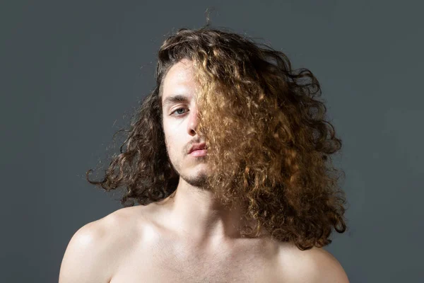 Férfi hosszú göndör hajjal, frizurával, modern frizurával. Közelkép férfi modellről hosszú hajjal. Egészségügyi és hajápolási koncepció. — Stock Fotó