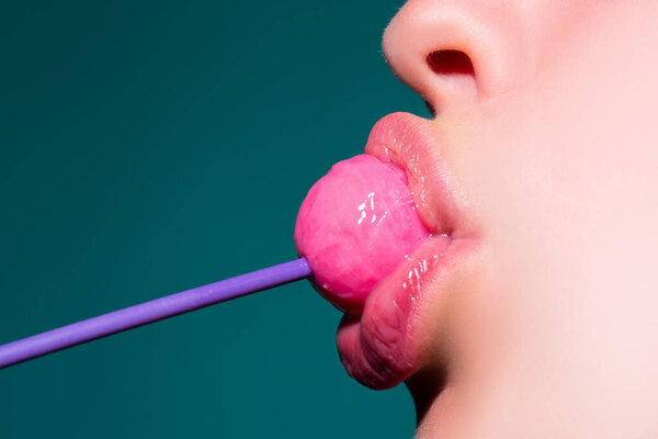 Леденец в рот, крупным планом. Красивый девчачий рот с леденцом. Блестящие красные женские губы с языком. Рот лизать сосет чупа-чупы.