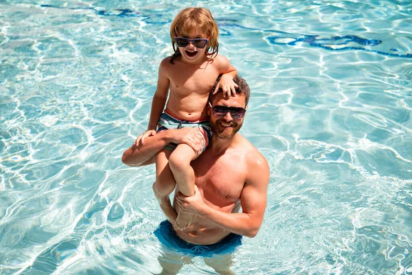 Vader en zoon in het zwembad. Familie heeft plezier op zomervakantie. Zwembadfeest. Kind met papa die in het zwembad speelt. — Stockfoto