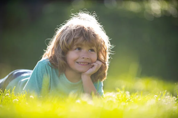 Портрет маленького хлопчика, що лежить на траві в літньому природному парку . — стокове фото