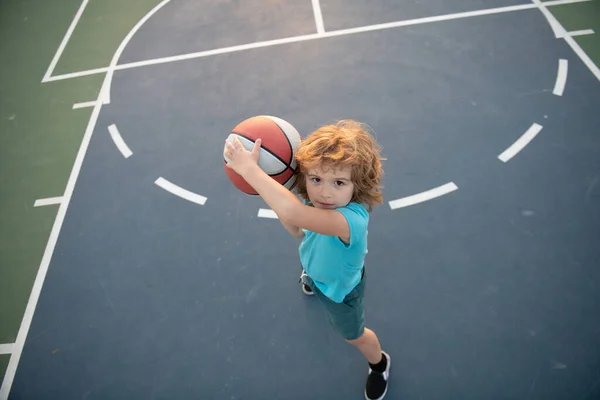 O miúdo concentrou-se em jogar basquetebol. Basquetebol crianças escola. — Fotografia de Stock
