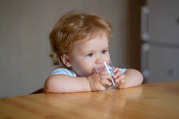 Baby drinkglas water. Gezonde voeding voor kinderen. Portret van kleine baby drinken in huiselijke omgeving. — Stockfoto