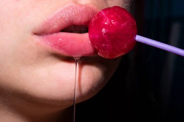 Şeker yalıyorum. Lolipop modeli. Kadın dudakları şeker emiyor. Oral seks konsepti. Kırmızı dudaklı çekici manken eşofman altı yiyor lolipop.
