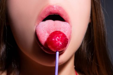 Seksi ağzı olan, chupa yiyen bir kız. Kadın dudakları lolipop emiyor. Ağzında lolipop tutan kadın, kapat. Kırmızı dudaklar, şehvetli ve seksi konsept..