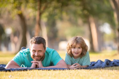 Baba ve oğul yaz parkında çimlerin üzerinde birlikte vakit geçiriyorlar..