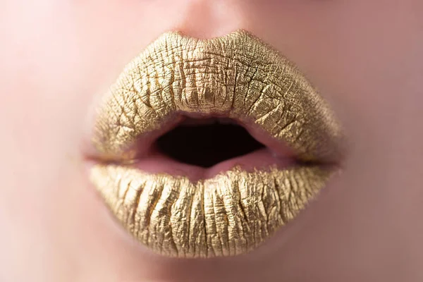 Guldläppar. Kvinna wouth närbild med gyllene färg läppstift på läppen. Glitter blanka läppar bita. — Stockfoto