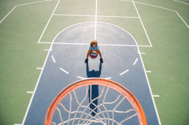 Çocuk bahçesinde basketbol oynayan çocuğun üzerinden açılı görüş.