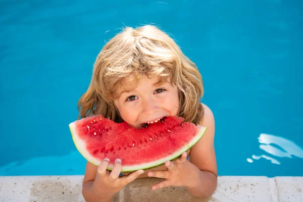 Divertido niño sorprendido come sandía cerca de la piscina. — Foto de Stock