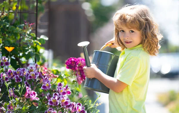Child pouring water on the trees. Kid helps to care for the plants in the garden. Little boy with a watering can on backyard. — Stock Photo, Image