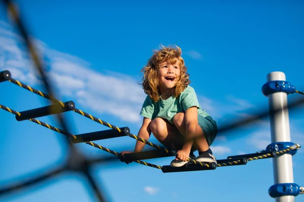 Χαριτωμένο αγόρι ανεβαίνει τη σκάλα στην παιδική χαρά. Το παιδί ανεβαίνει τη σκάλα πάνω στον γαλάζιο ουρανό. Αντιγραφή χώρου για κείμενο. — Φωτογραφία Αρχείου