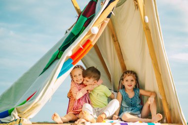 Erkek ve kız kardeşler birlikte oynuyorlar. Çadırda oynayan mutlu çocuklar. Kamp yapan sevimli çocuklar. Dışarıda eğleniyoruz. Kamp alanı.