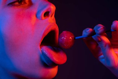 Lolipop yalayan baştan çıkarıcı kadın, sanat afişi, lolipoplu kırmızı dudaklar. Lolli pop ile seksi kırmızı kadın ağzı ve dili. Neon ışıkların tasarımı için sanat baskısı. Gece kulübü geçmişi.