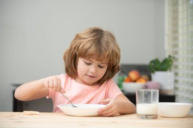 Kafkasyalı küçük çocuk mutfakta sağlıklı çorba içiyordu. Evde lezzetli yulaf lapası ya da mısır gevreği yiyen, mutfaktaki masada oturan şirin çocuğun yakından çekilmiş yüzü..