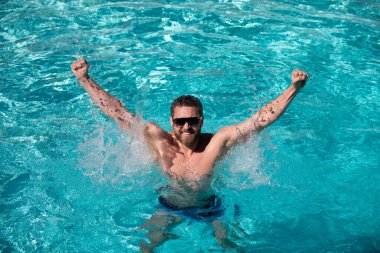 Havuz tatili. Havuzda mutlu bir adam. Yaz tatili. Güneş gözlüklü adam yüzme havuzunda dinleniyor..