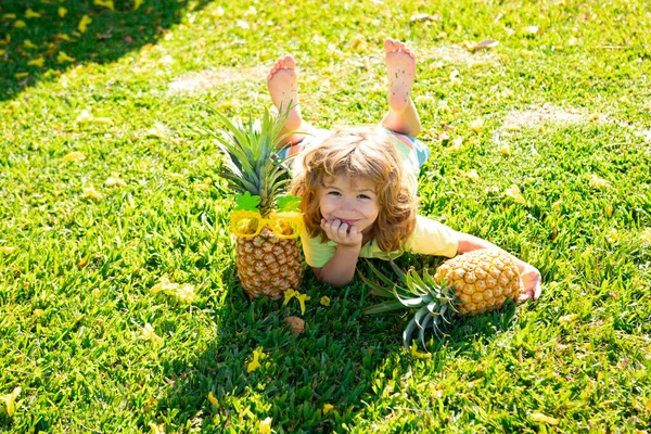 Little blonde kid hugging pineapple on nature background. Childhood, healthy nutrition, advertising. Close up kids funny face, copy space. — Stock Photo, Image