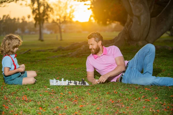 Happy family outdoor. Father and son playing chess in summer garden. Little boy play chess with parent. Cognitive development. Intellectual kids game. Smart children. — Stock Photo, Image